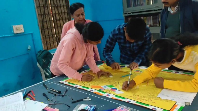 Students bent over a large yellow wall magazine