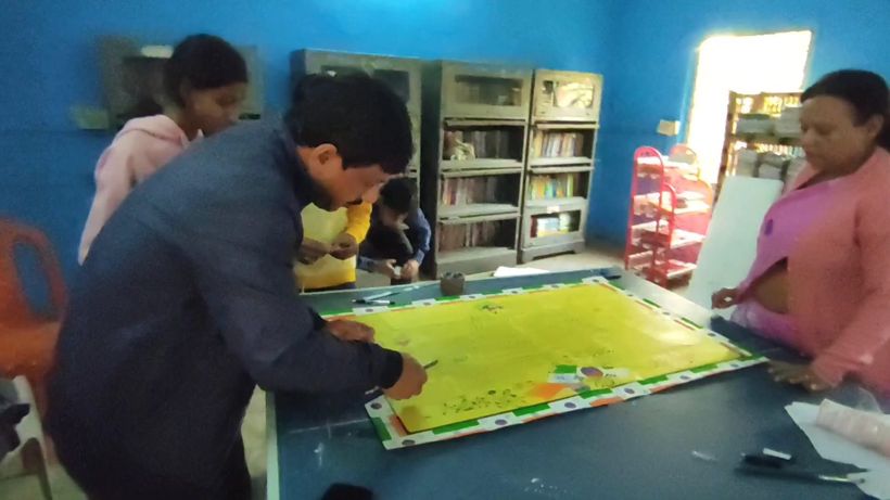 A teacher helps students finish the wall magazine