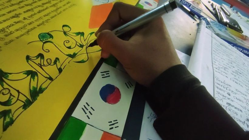 Close-up of a hand inking a design beside painted flags
