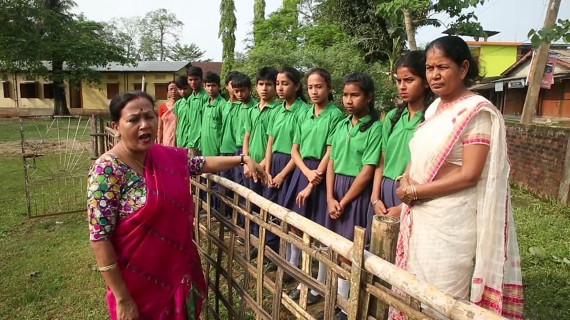 Principal Shyamalima Borah, left, with students in green uniforms on the grounds