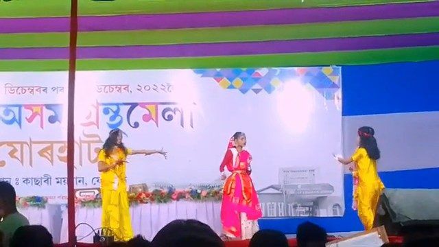 Three girls dancing on a colourful book-fair stage