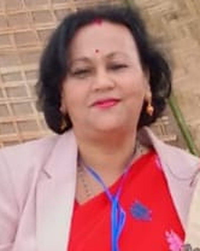 Principal Shyamalima Borah, smiling, in a red saree and pink jacket