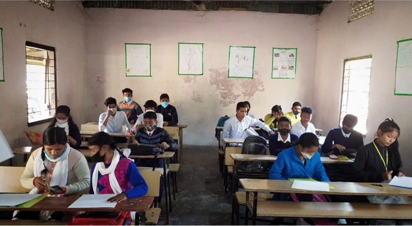 Students seated at desks in a classroom with pink walls