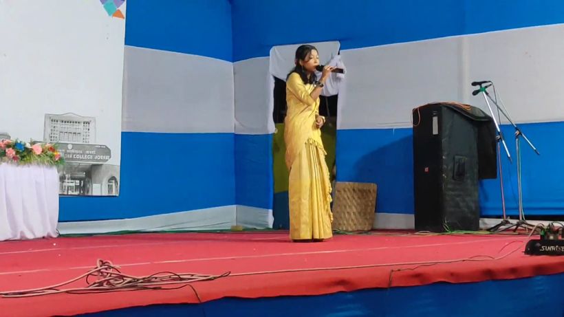 A girl in mekhela singing on stage