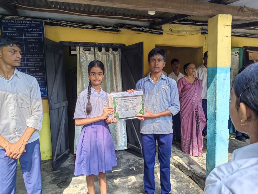 Two students holding an International Vulture Awareness Day certificate outside the school office